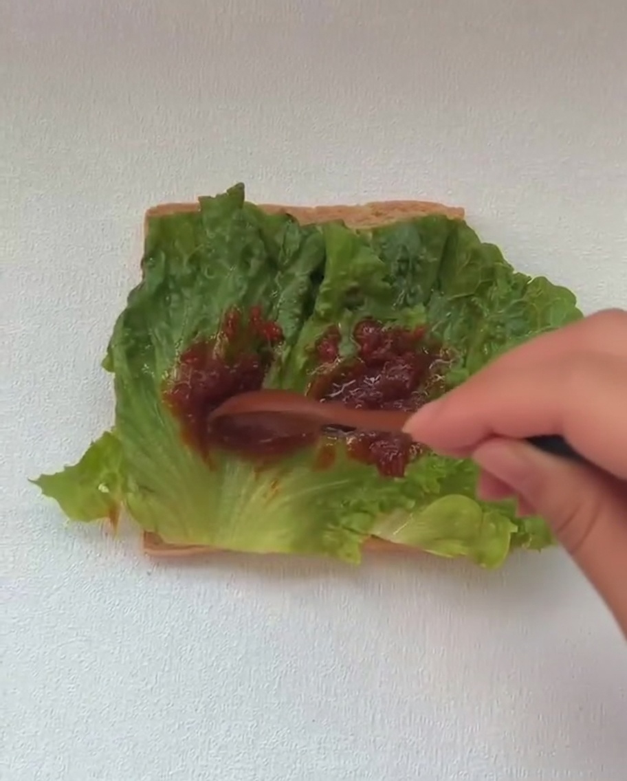 レタスの層の上に焼きたての目玉焼きを乗せている様子。