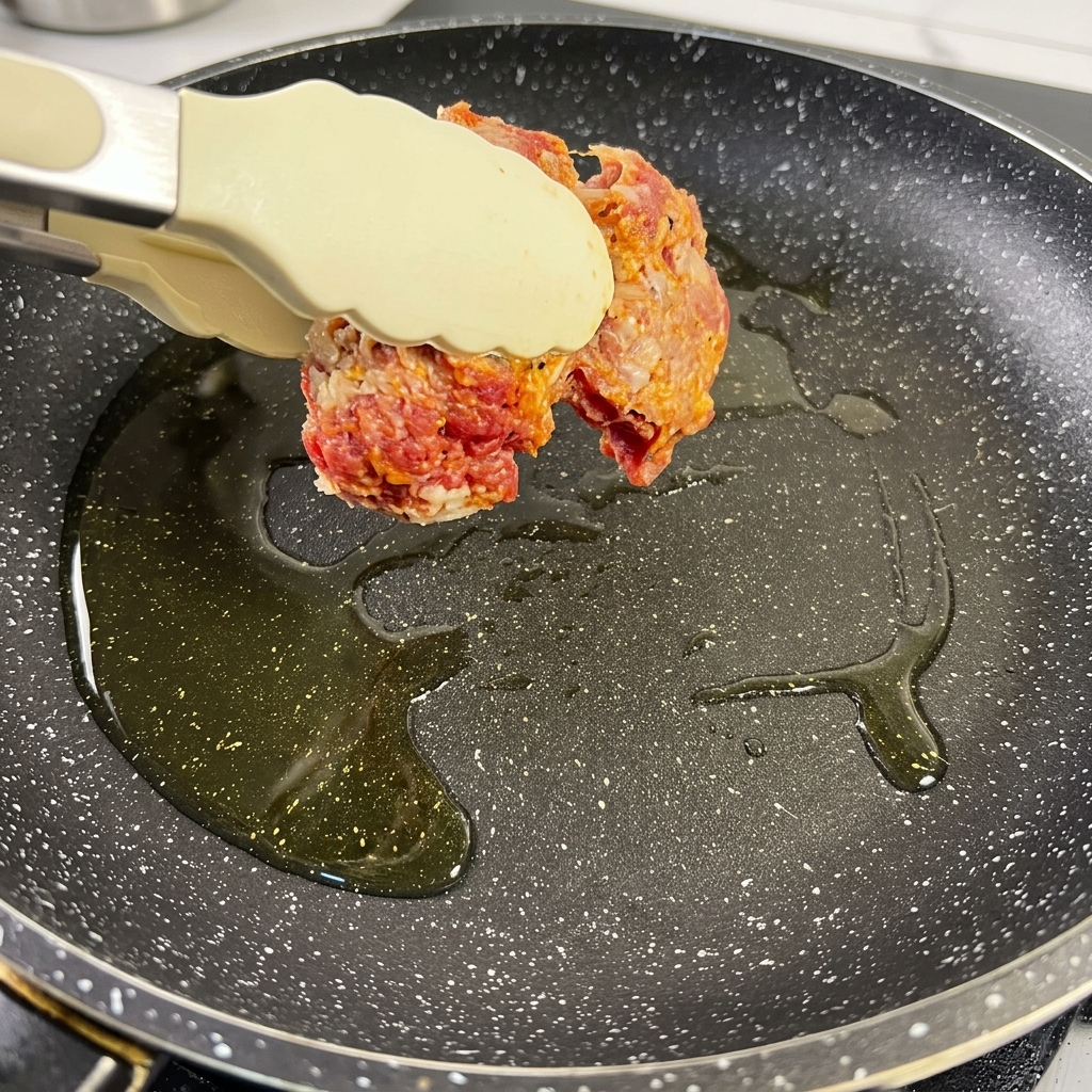 熱したフライパンで、シーズニングされた牛ブリスケットの表面をこんがりと茶色く焼いている様子。