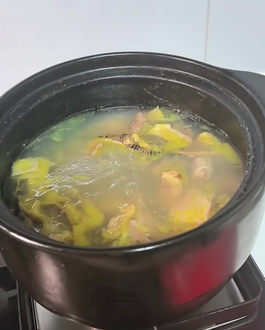 コンロで煮立っている黒い鍋に入ったチキンスープ。
