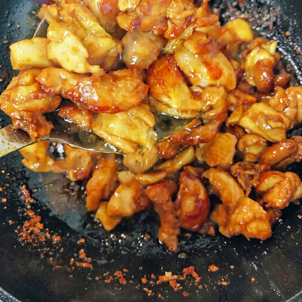 焼き色がついた鶏肉と、生姜やネギ、唐辛子を一緒に炒めている様子。