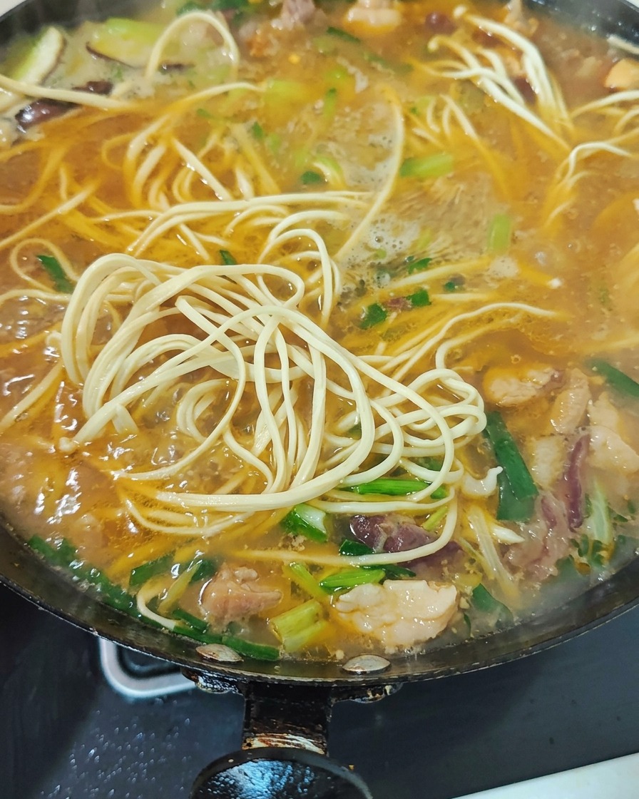 青菜とニンニクの芽を煮込み、彩り鮮やかに仕上げている様子。