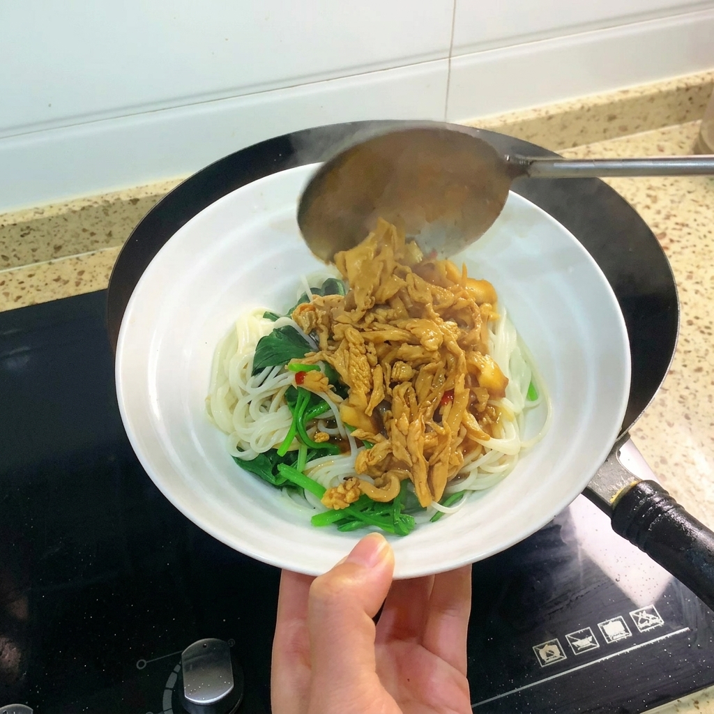 茹でた麺の上に、たっぷりの鶏肉と厚揚げ、ソースをかけている様子。