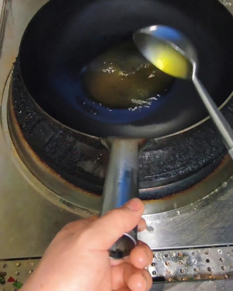 熱した中華鍋に油を注ぐ様子。