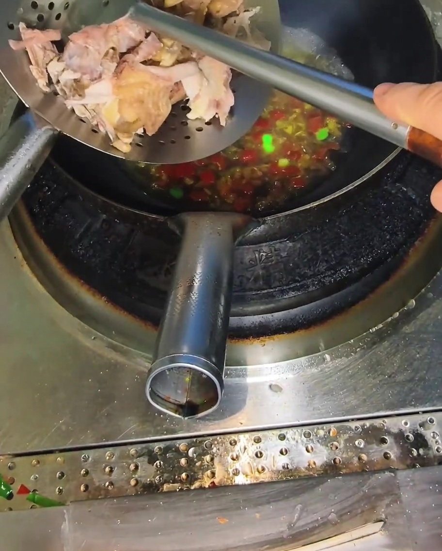 沸騰したスープにほぐした鶏肉を加える様子。