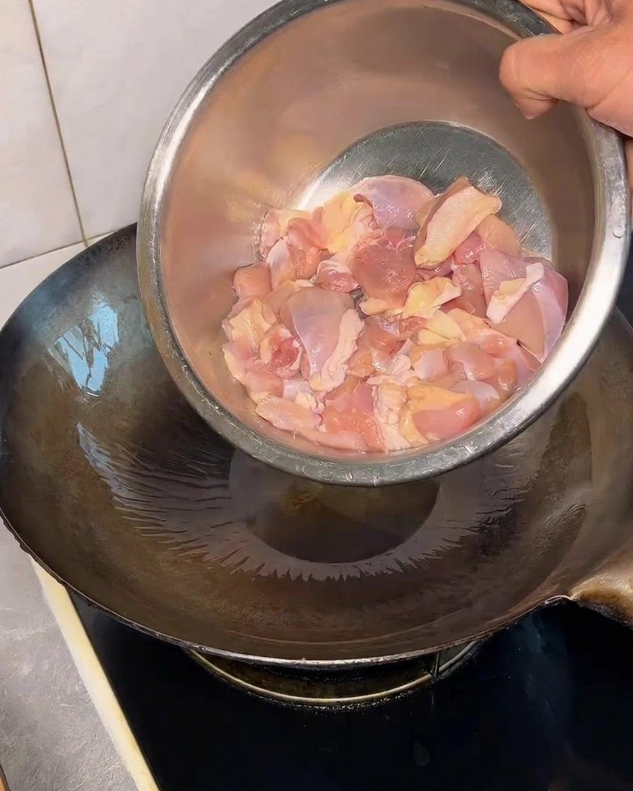 油を引いた熱い鍋に鶏もも肉を投入する様子。