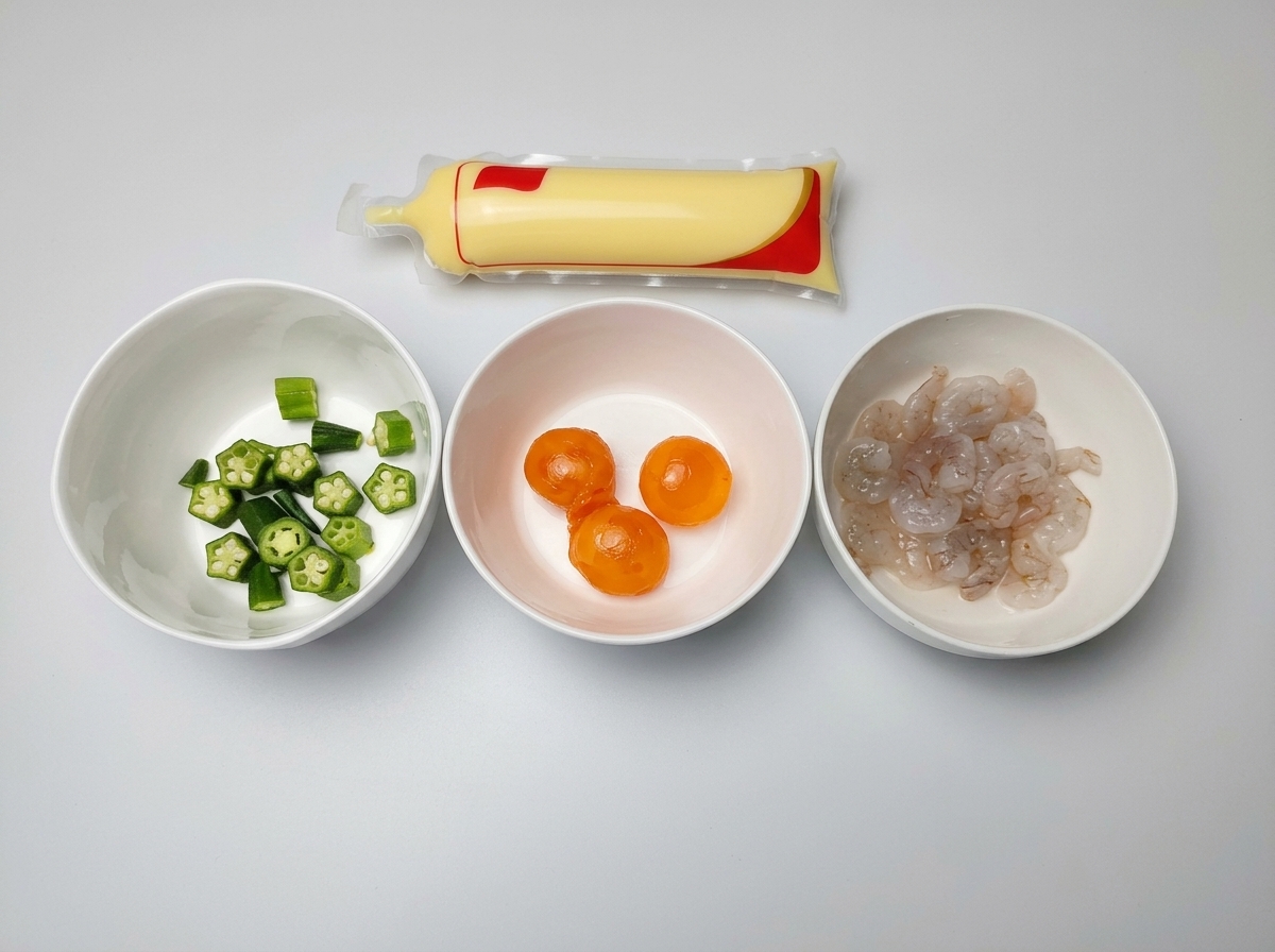 切ったオクラ、塩漬け卵黄、生の海老がそれぞれ白い小鉢に入っており、隣に卵豆腐のパックが置かれている様子。