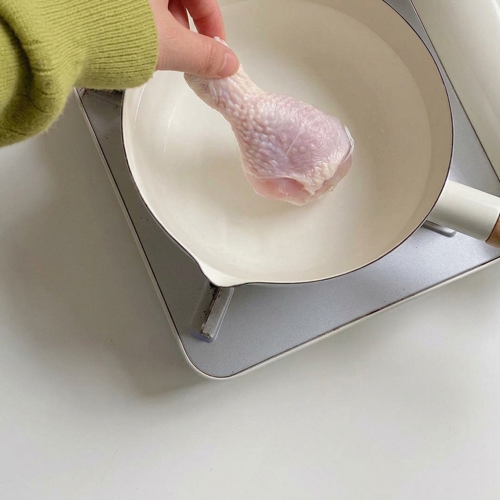 鍋で生姜や長ねぎと一緒に鶏肉を下茹でしている様子。