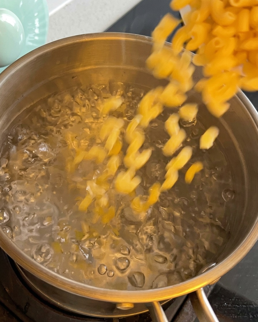 沸騰した湯にマカロニを入れる様子