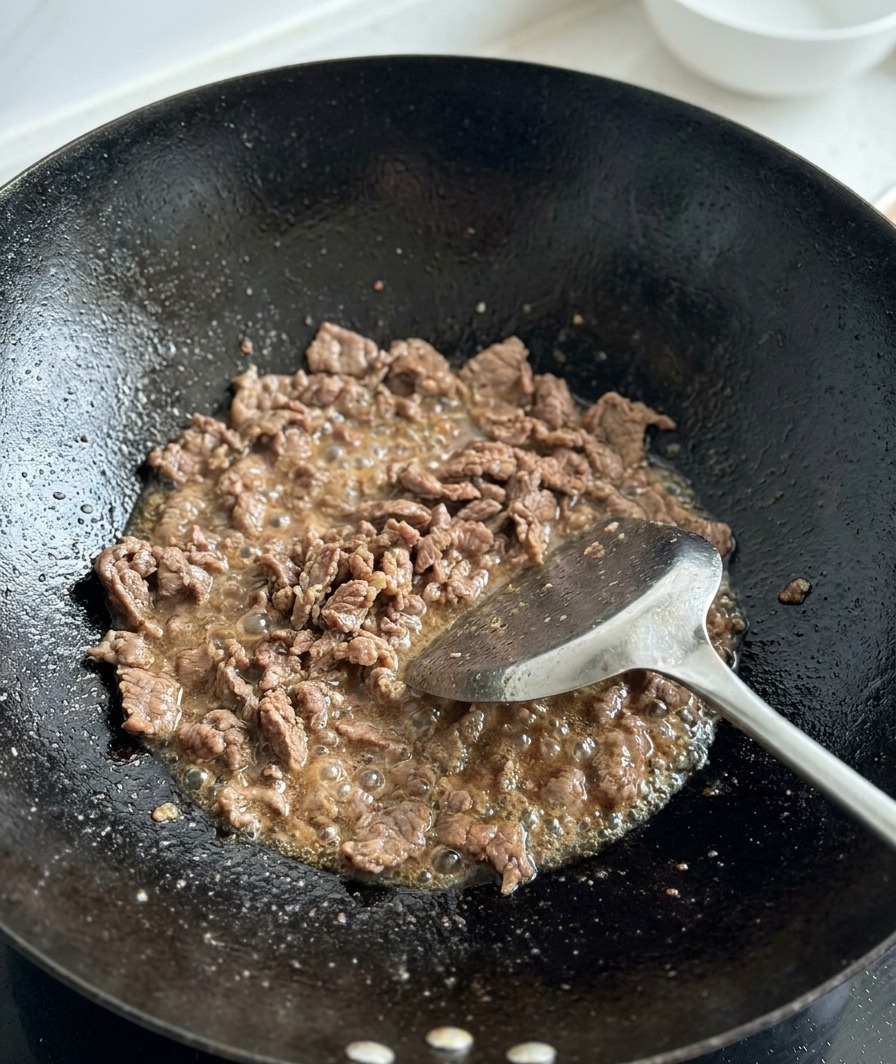 炒めた肉に角切りトマトを加える様子