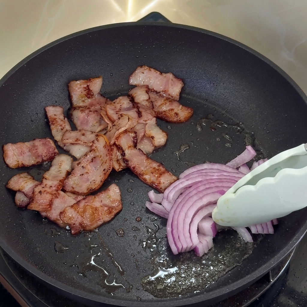 ベーコンの脂で玉ねぎを炒めている様子