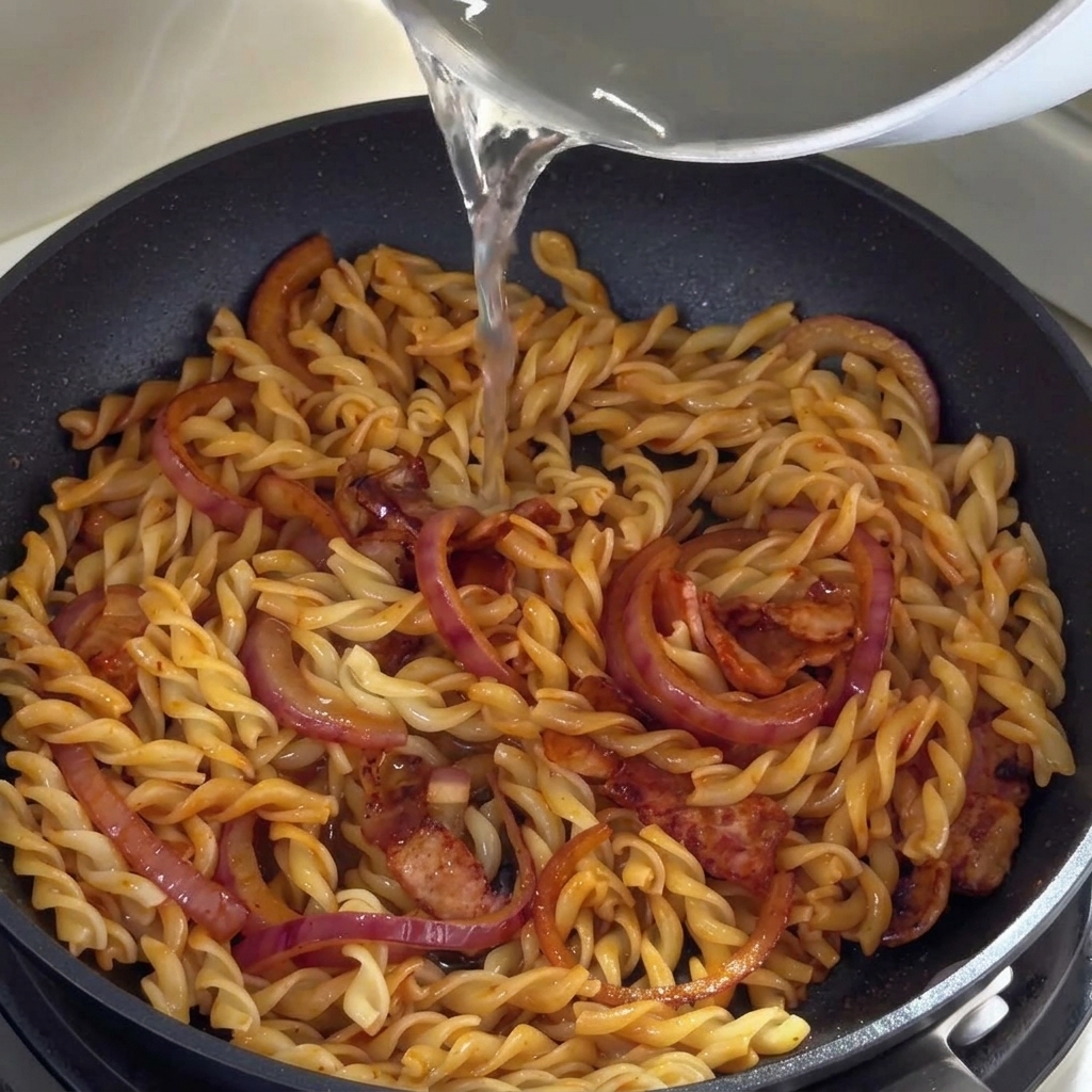 パスタの茹で汁をフライパンに加えている様子