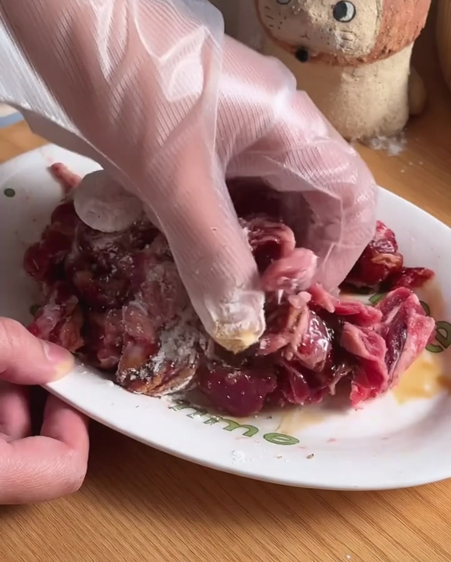 白いボウルの中で、調味料と牛肉が混ぜ合わされている様子。
