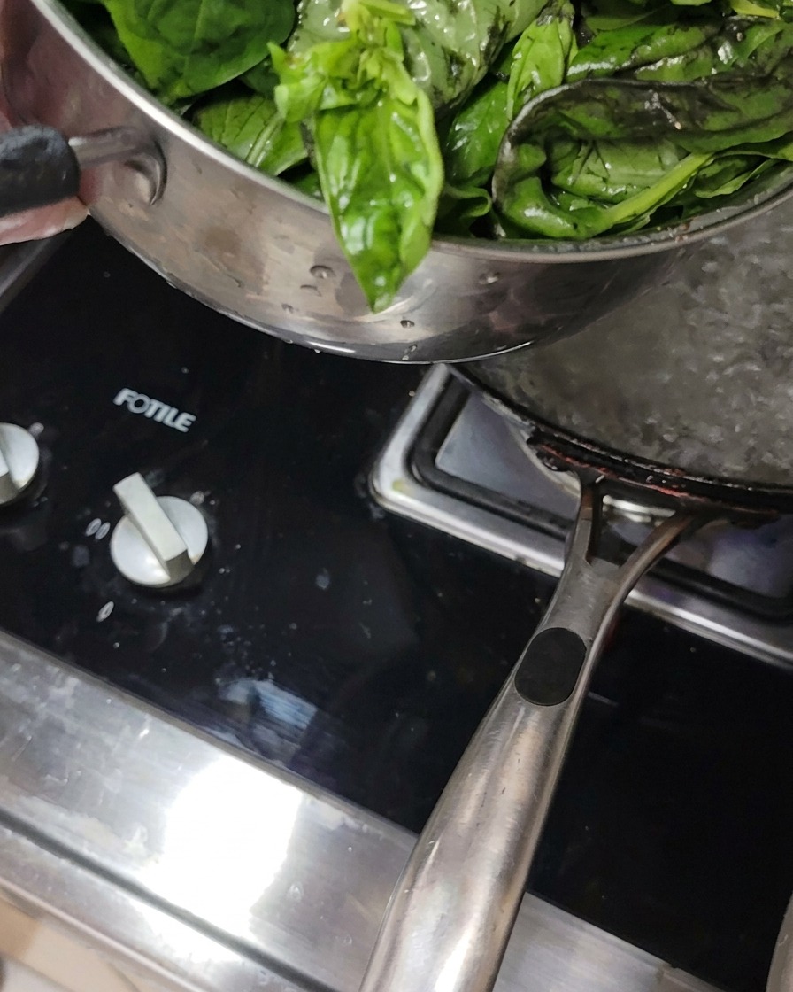 鍋で沸騰したお湯にバジルの葉を入れている様子。