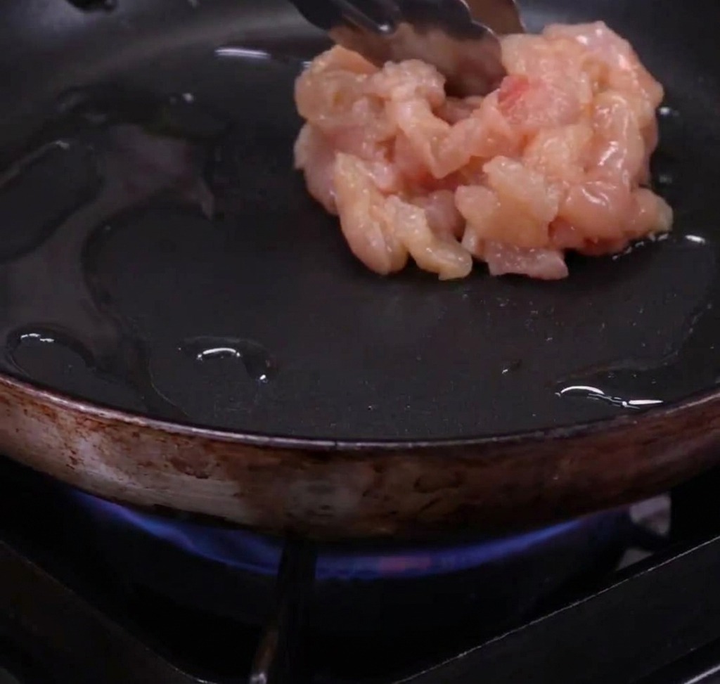 フライパンでオリーブオイルを熱し、鶏肉を焼いている様子。