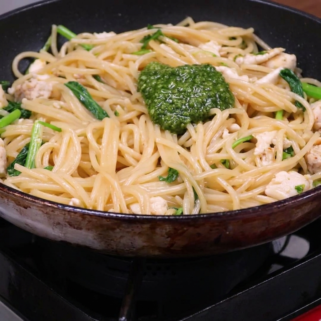 パスタの上に鮮やかな緑色のペーストをのせている様子。