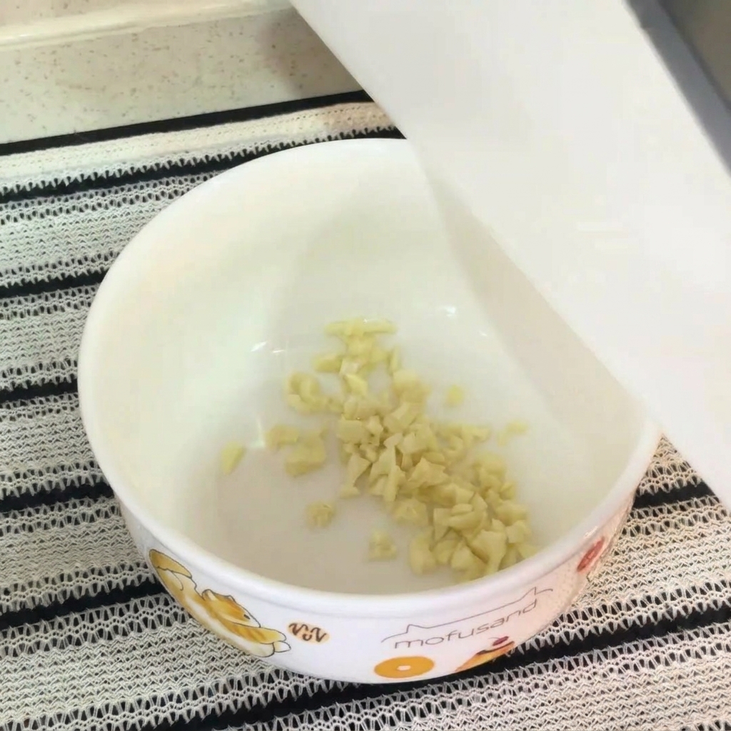 白いボウルに、刻んだにんにく、生卵の卵黄、調味粉末、マヨネーズが入り、混ぜ合わせる直前の様子。