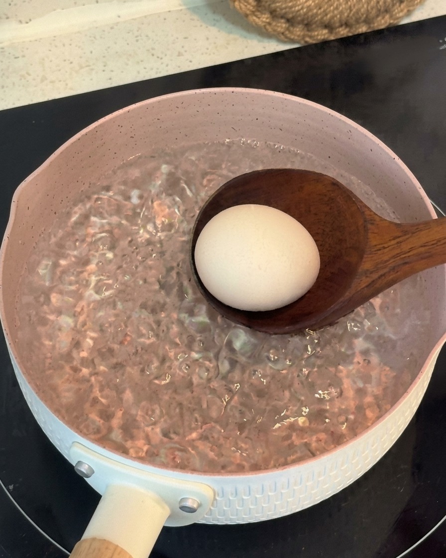 沸騰した鍋に、レードルを使って静かに全卵を入れている様子。