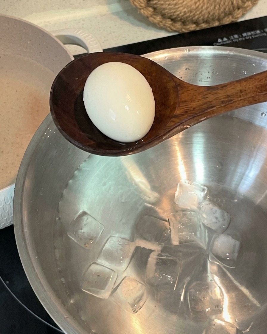 茹で上がった卵を、氷水を入れたステンレスのボウルに移動させている様子。