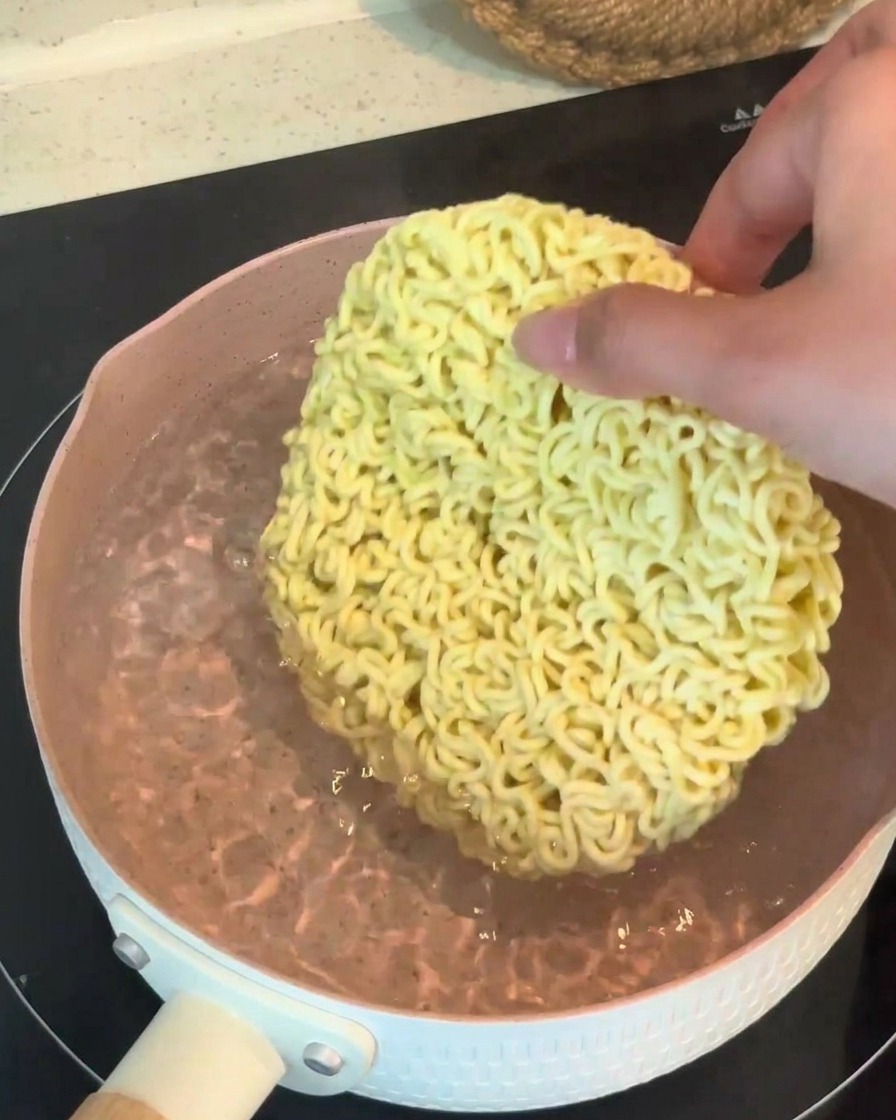 沸騰したお湯に、インスタント麺の乾麺を投入している様子。