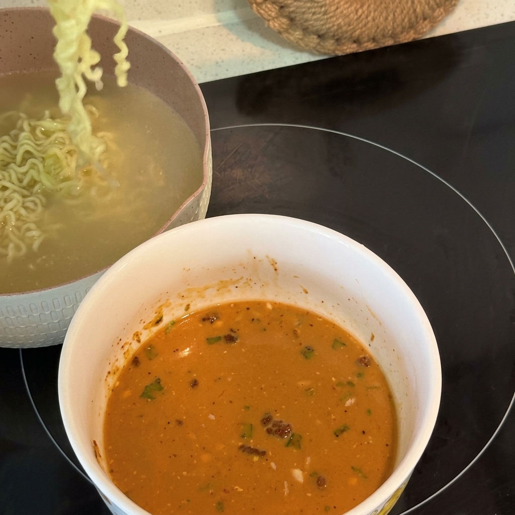 茹で上がった麺を、クリーミーなスープが入った器に移している様子。