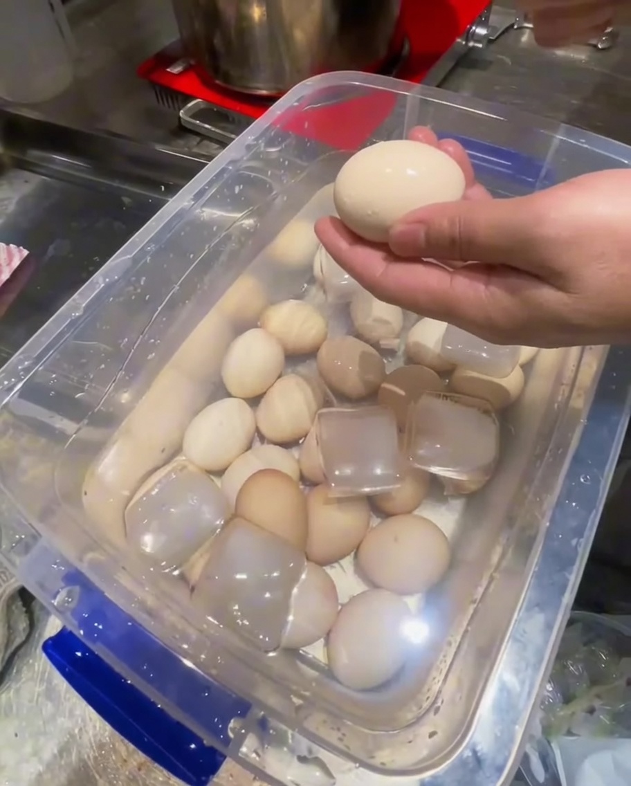 冷えた卵の殻を金属製のスプーンを使って剥いている様子。
