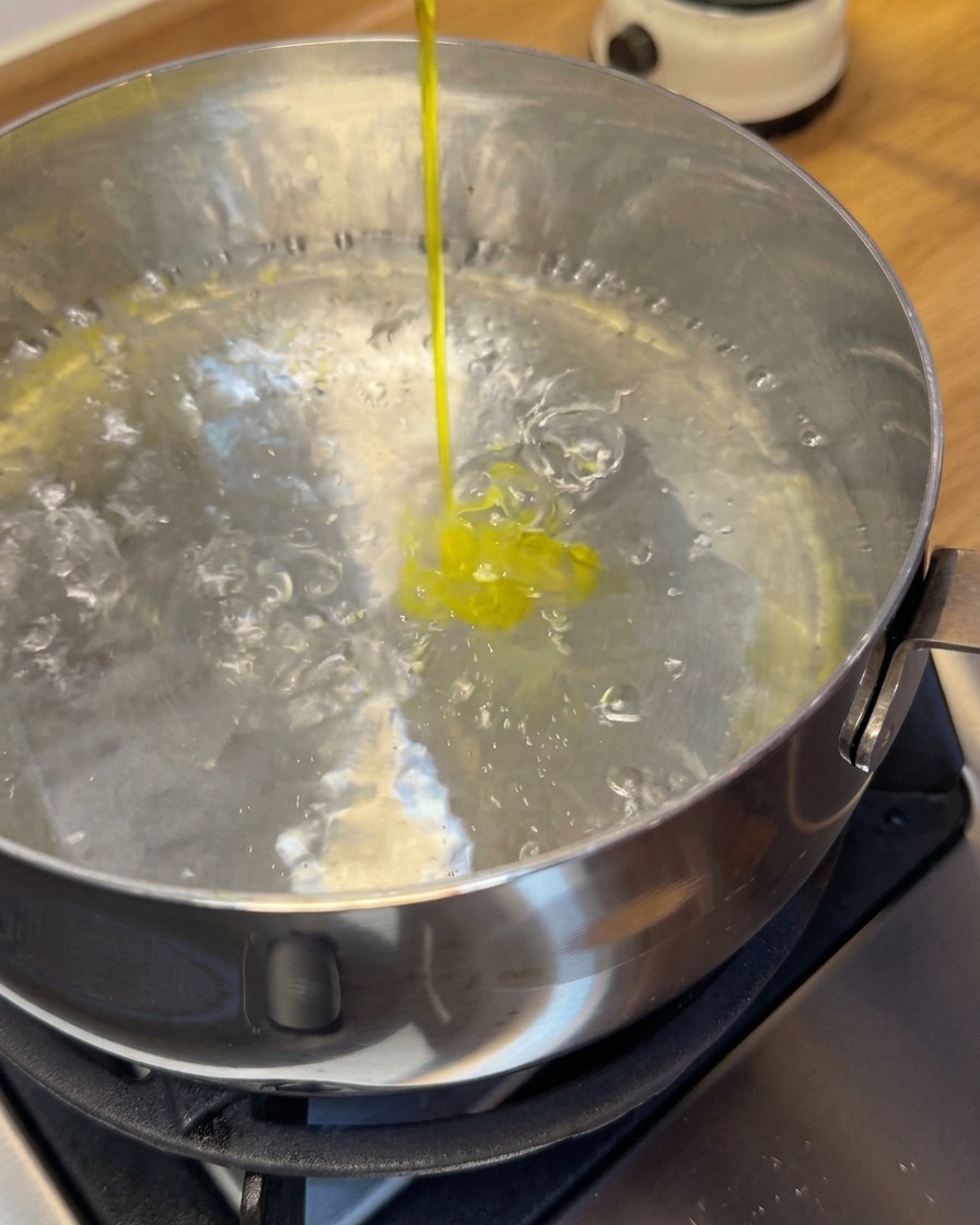 穴あきお玉を使って、沸騰したお湯に海老ワンタンを投入している様子。