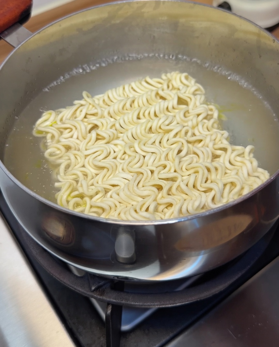 沸騰した湯の中でインスタント麺が茹でられている様子。
