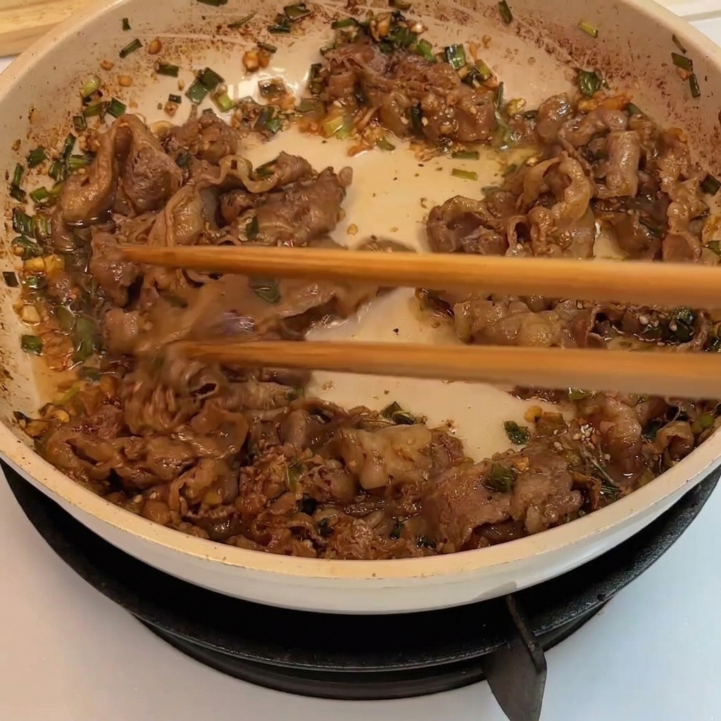 フライパンで牛肉に焼き色がつき、火が通るまで炒めている様子。