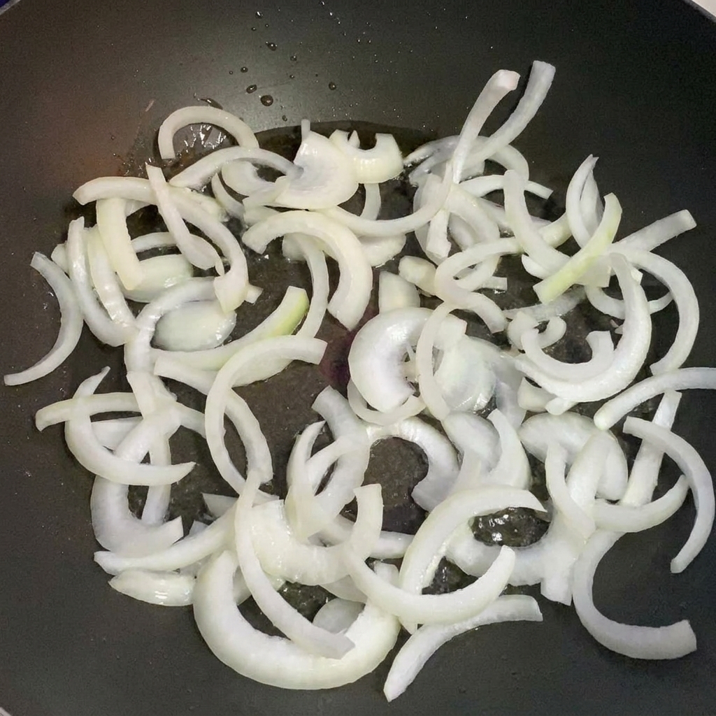 熱したフライパンでスライスした玉ねぎを炒めている様子