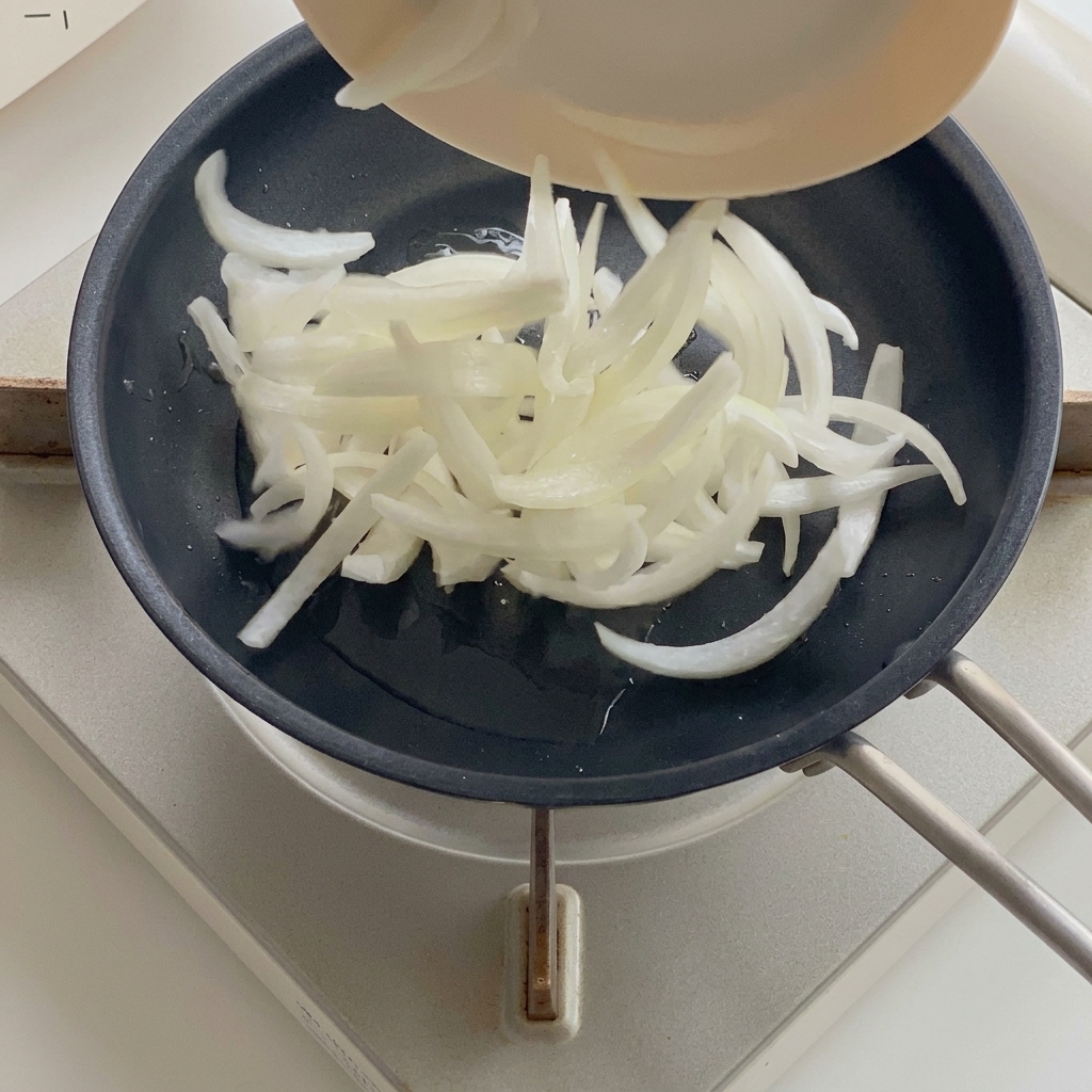 フライパンで油を引いて玉ねぎを炒めている様子。