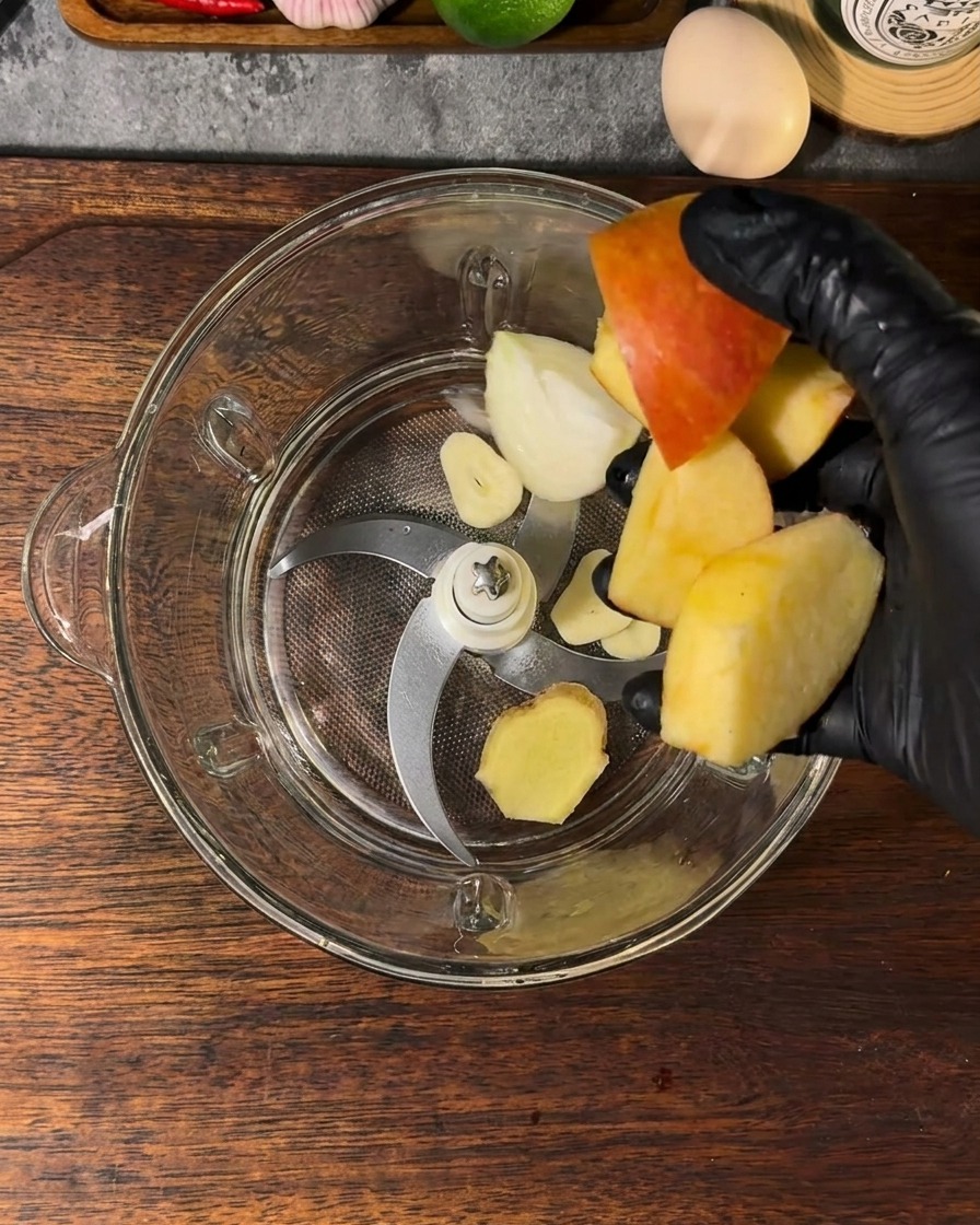 ブレンダー容器にカットしたリンゴ、玉ねぎ、にんにく、生姜、水が入っている様子。