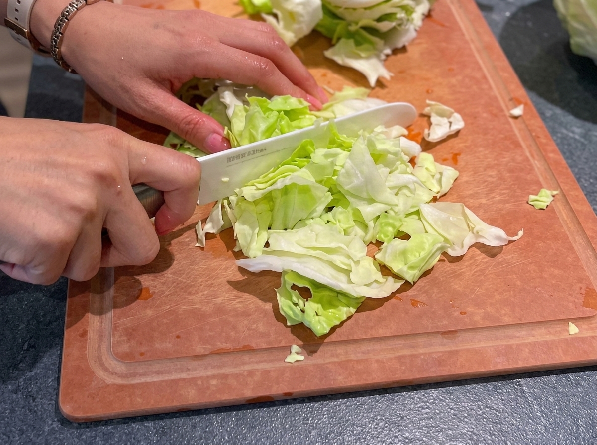 まな板の上でキャベツを包丁で刻んでいる様子。