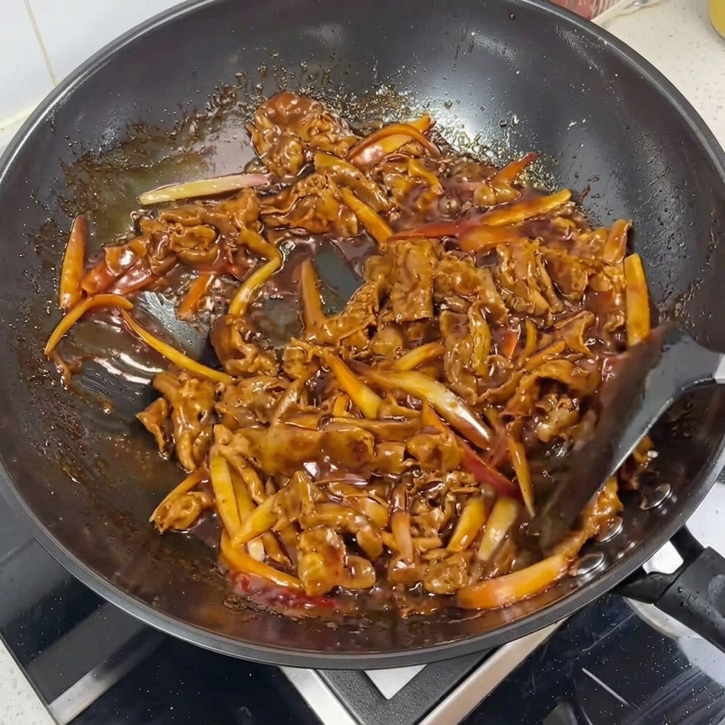中華鍋の中でツヤのある照り焼きダレが絡んだ牛肉と赤玉ねぎのアップ。