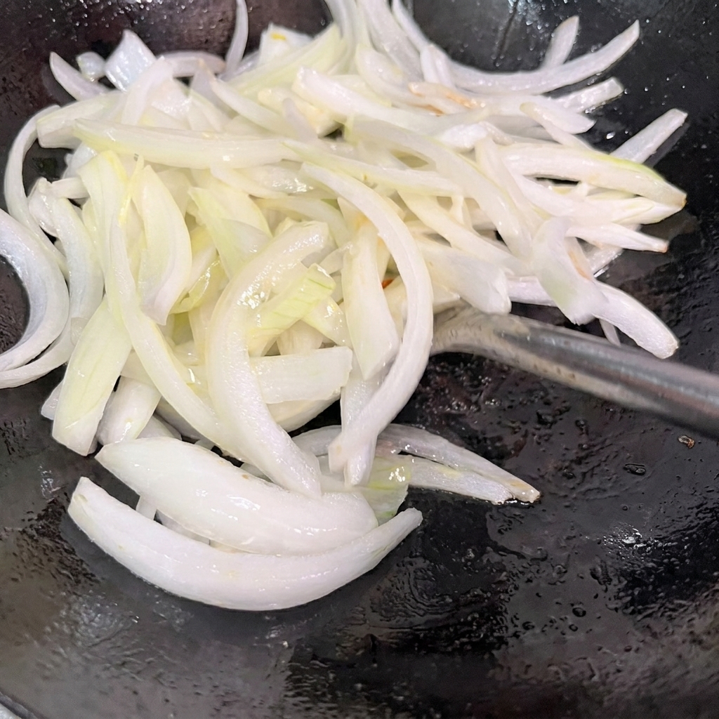 熱した中華鍋で玉ねぎを炒める様子。