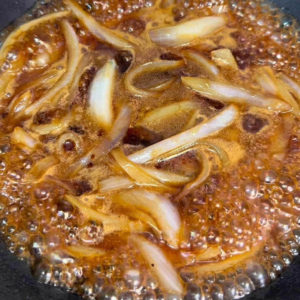 湯通しした牛肉を鍋に加え、タレと絡める様子。