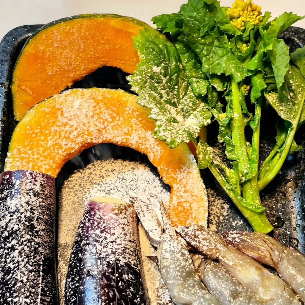 バットの上で、かぼちゃ、なす、海老に薄く粉をまぶしている様子。