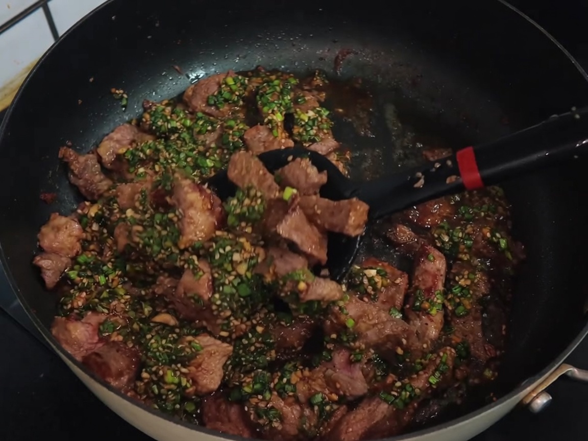 フライパンで肉とネギ塩ダレをさっと炒め合わせている様子。