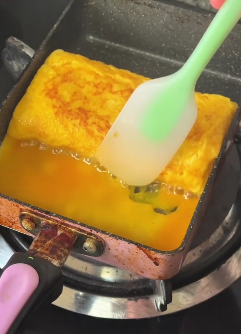 焼き上がった厚焼き玉子をヘラで整えている様子。