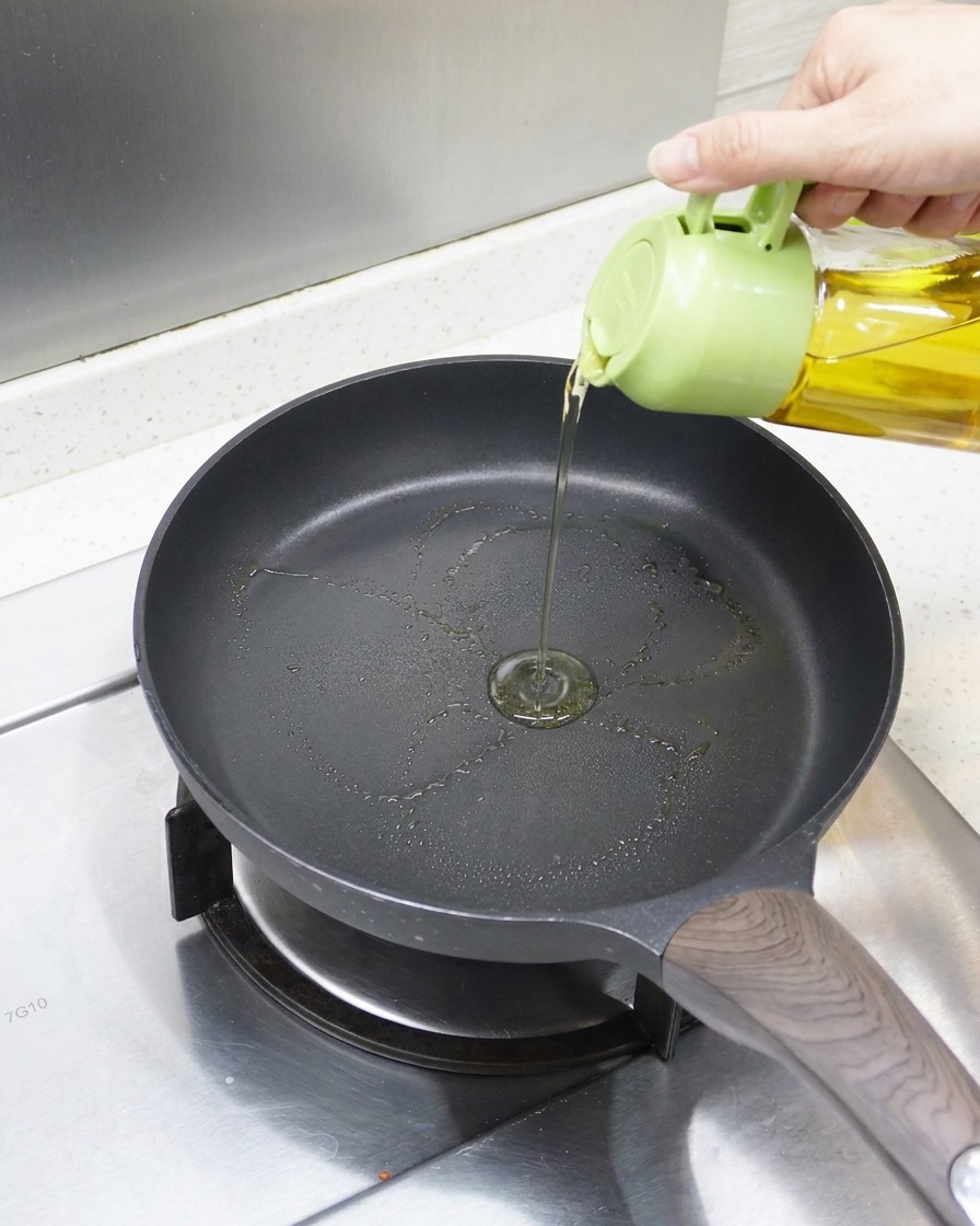 予熱したフッ素樹脂加工のフライパンに油をひいている様子。