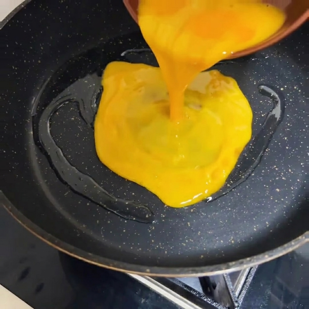 熱したフライパンに溶き卵を流し込んでいる様子。