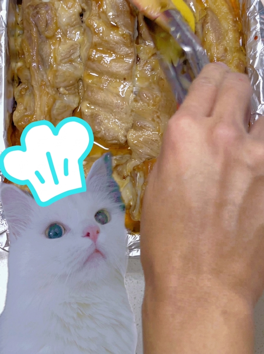 ご飯と卵の上に、タレを絡めた鰻をトングで丁寧に盛り付けている様子。