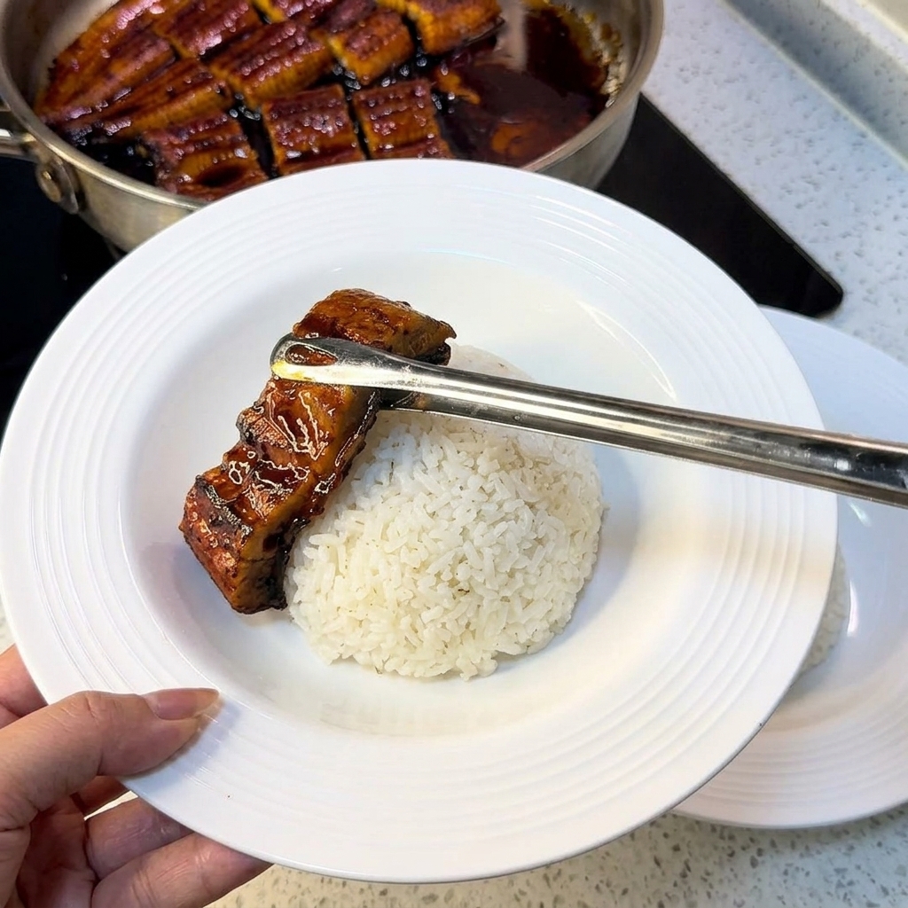 どんぶりに入ったご飯の上に、うなぎと錦糸卵を盛り付けている様子。
