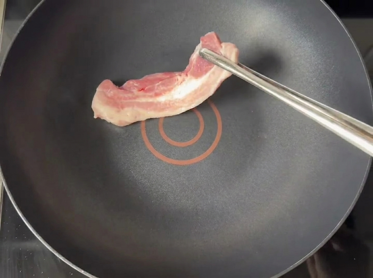 油をひかないテフロン加工のフライパンでこんがりと焼かれている豚バラ肉のスライス。