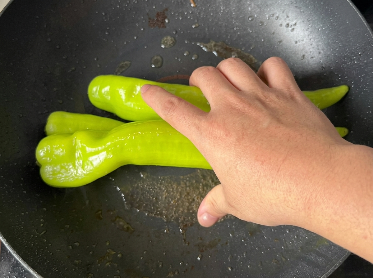フライパンで皮に焦げ目がつくまで焼かれているピーマン。