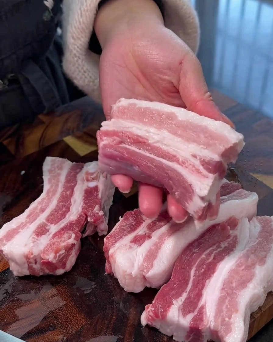 まな板の上で豚バラ肉を均一な厚さの細切りにしている様子