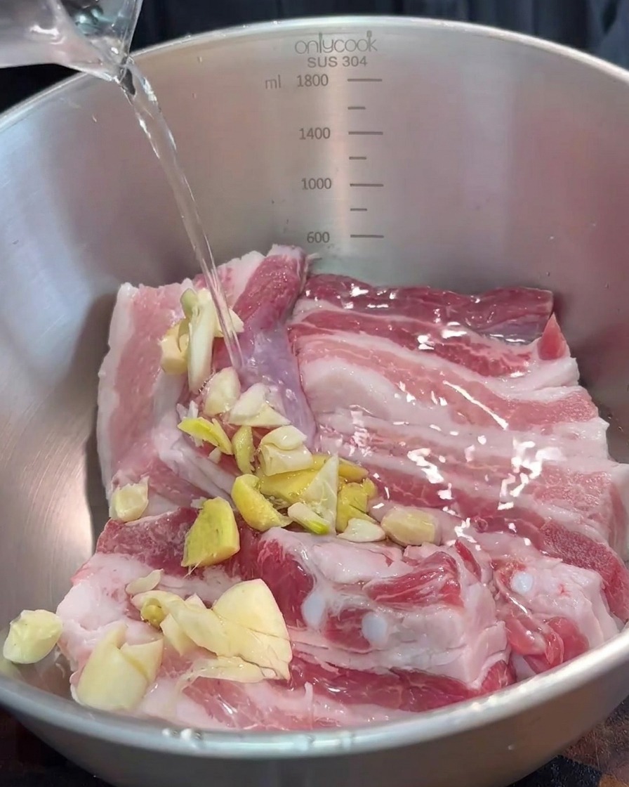 ボウルに入った豚肉に、刻んだ香味野菜と紅腐乳を加えている様子