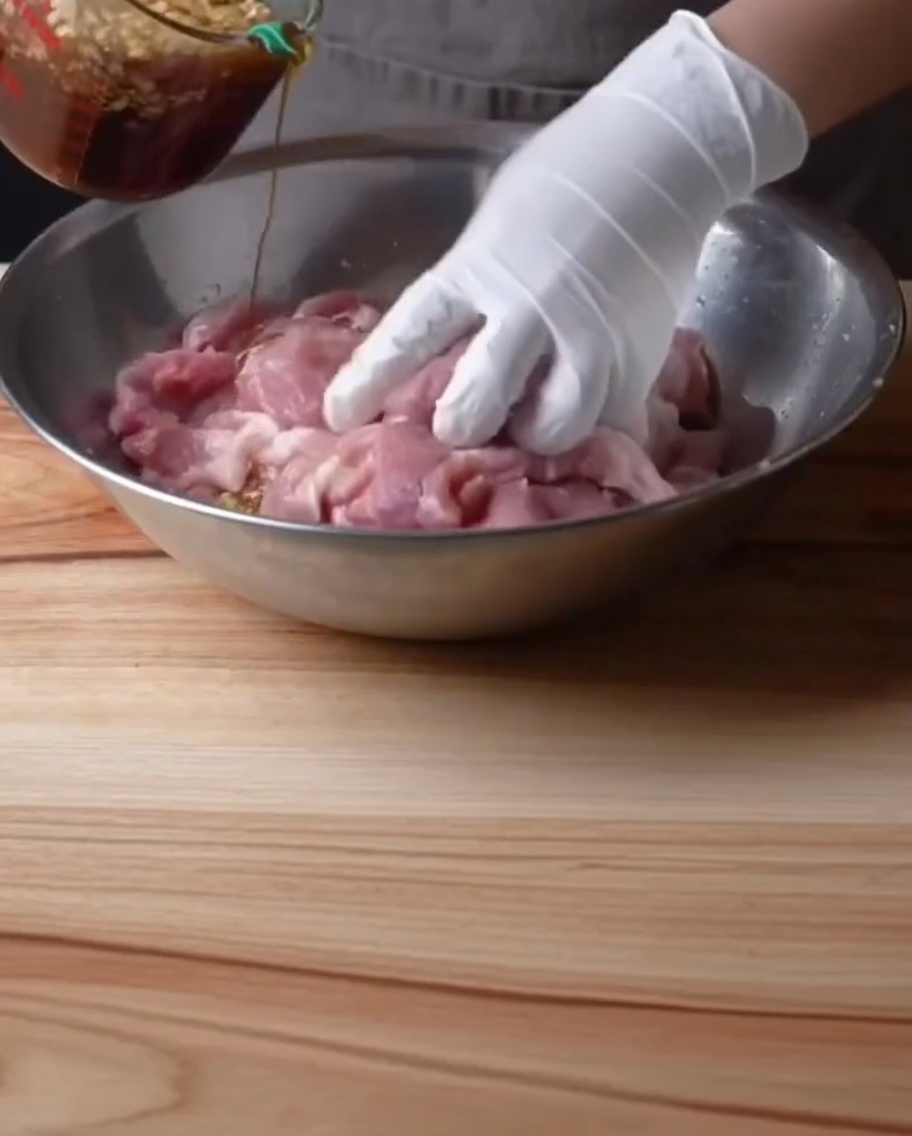 下味をつけた豚肉にタレを回しかけている様子。