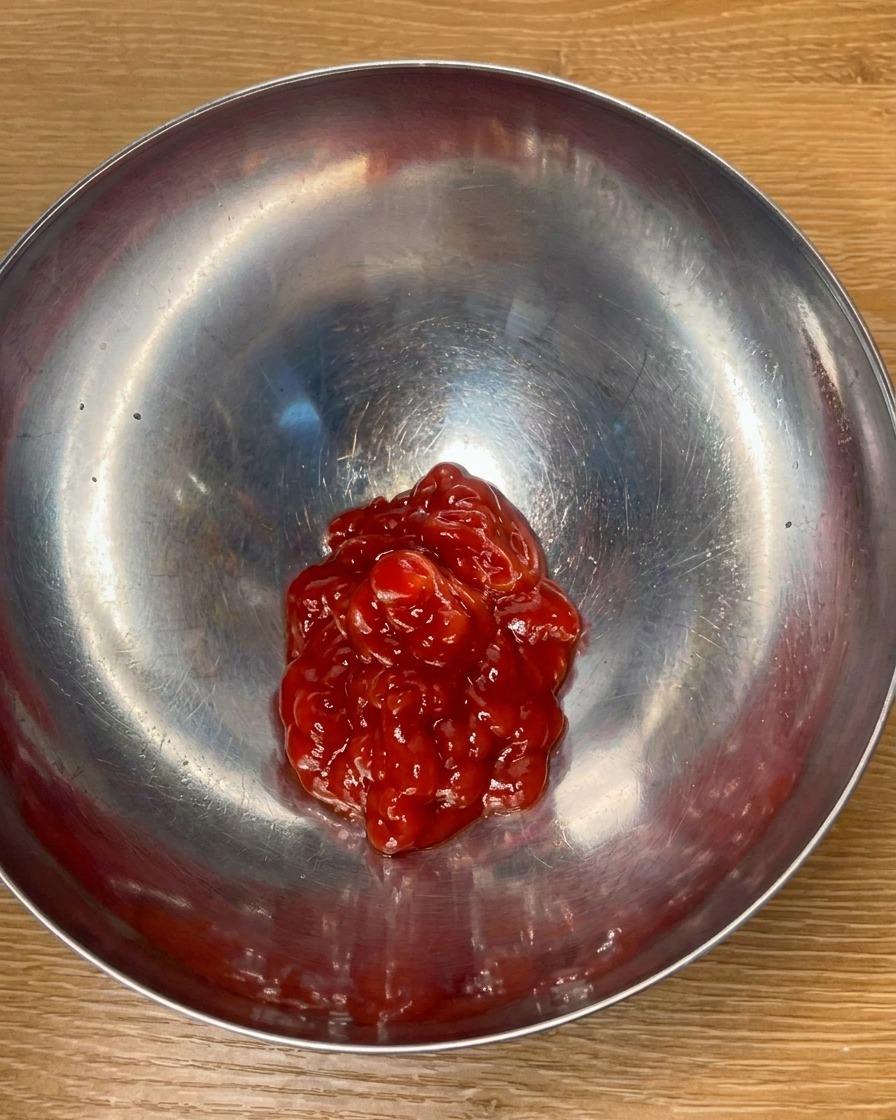 金属製のボウルでトマトケチャップと調味料を混ぜ、ソースを作っている様子。