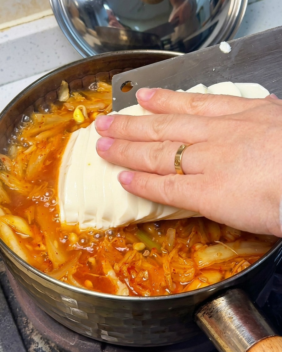 沸騰した赤いスープに絹ごし豆腐をそっと加える様子。