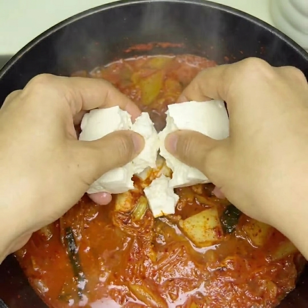 煮立っている赤いスープに豆腐を丁寧に入れている様子。